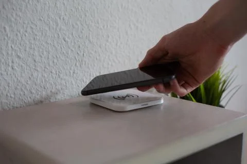 Smartphone being placed on wireless charging pad to charge Stock Photos