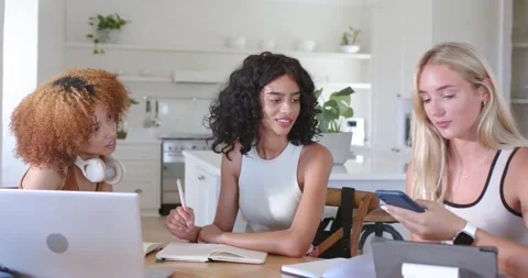 Smartphone being tapped is tilting toward notebook and laptop on kitchen table Stock Footage 337098763