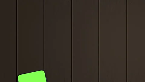 Smartphone with a blank green screen, front view, on the brown wooden Stock Footage 161952179