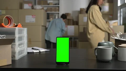 Smartphone with blank green screen standing on the desktop in the warehouses. Stock Footage 172285602