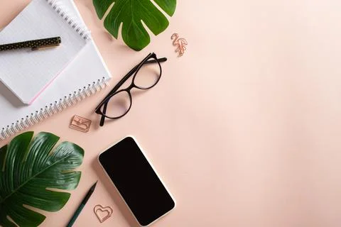 Smartphone, blank notepad, monstera flower leaf, glasses, pen, paper clips, p Foto stock