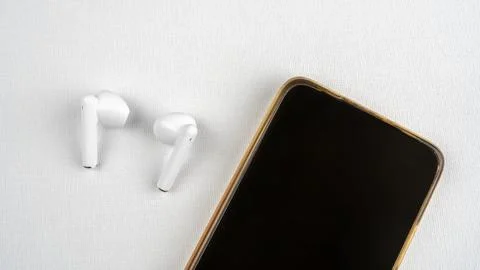 Smartphone with blank screen and wireless headphones next to it on white Stock Photos