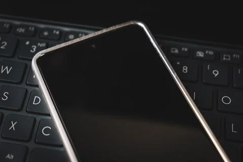 Smartphone with blank screen on a computer keyboard. programming application  Stock Photos