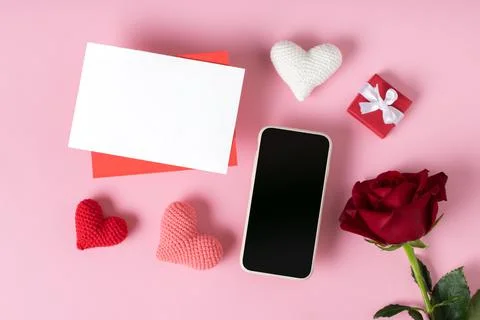 A smartphone with a blank screen, an envelope, a red rose, a gift and knitted Stock Photos