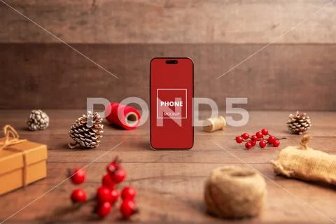 Smartphone with blank screen standing in festive Christmas scene with pinec.. PSD Template