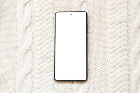 Smartphone with a blank white screen against a warm knitted sweater. Template Stock Photos