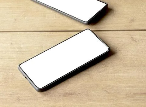 A smartphone with a blank white screen overlaps its mirror reflection on a .. Stock Photos