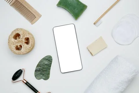 Smartphone with blank white screen surrounded by natural skincare and self-ca Stock Photos
