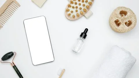 Smartphone with blank white screen surrounded by natural skincare and self-ca Stock Photos