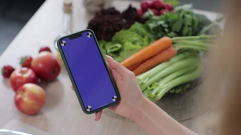 Smartphone with blue screen for chroma key in hand of woman in kitchen Stock Footage 244803898