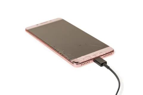 Smartphone with broken screen charging via cable isolated on white background Stock Photos
