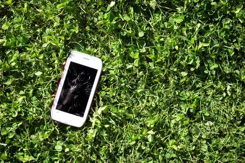Smartphone with broken screen lying on the grass Stock Photos