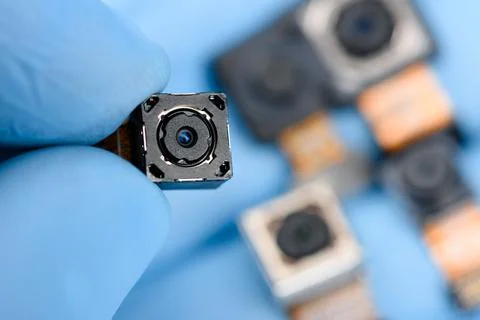 Smartphone camera module in researcher hand, with other cell phone sensor Stock Photos