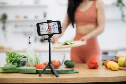 Smartphone capturing salad cooking process by lady at home Stock Photos