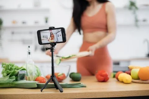 Smartphone capturing salad cooking process by lady at home 写真素材