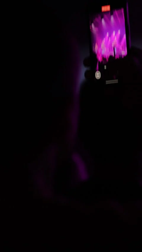 Smartphone capturing vibrant concert performance with colorful lights and Stock Footage 313639988