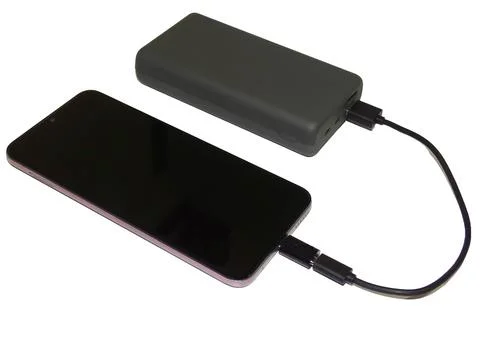 A smartphone charges from an external battery Фото
