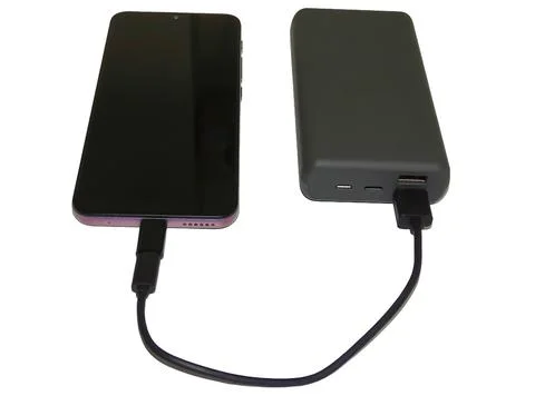 A smartphone charges from an external battery 스톡 사진