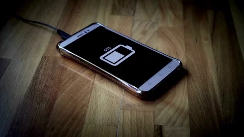 Smartphone charging animation from empty to full on wooden floor Stock Footage 335651950