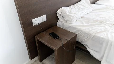 Smartphone Charging on Bedside Table in Modern Hotel Room Stock Photos