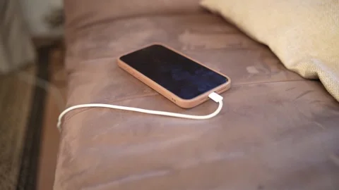Smartphone charging with a cable on a sofa 스톡 동영상 328228730