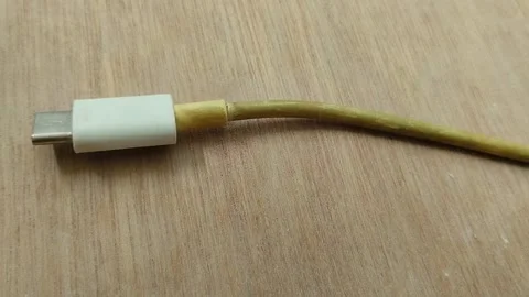 Smartphone charging cable turns yellow on wood texture background 스톡 동영상 296865575