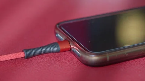 Smartphone charging with red fabric cable close up view on textured leather.. Stock Footage 332029534