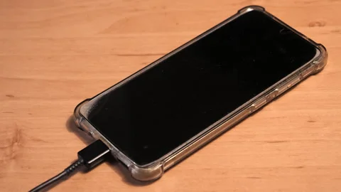 Smartphone charging on table. Slider shot from charging cable to phone. Stock Footage 259987819