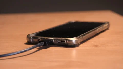 Smartphone charging on table. Slider shot from charging cable to phone. Stock Footage 259987823