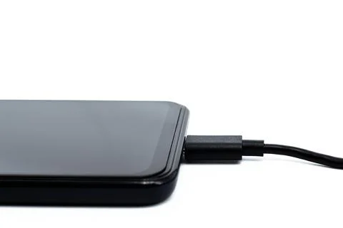 Smartphone charging via usb cable on a white background. Wired charging Stock Photos