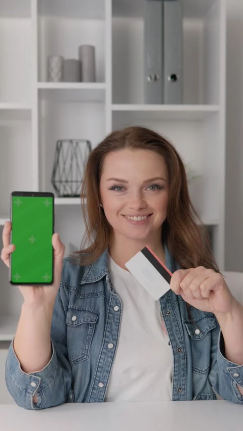 Smartphone chroma key green screen woman holding in hand. A woman happily pays Stock Footage 266400890