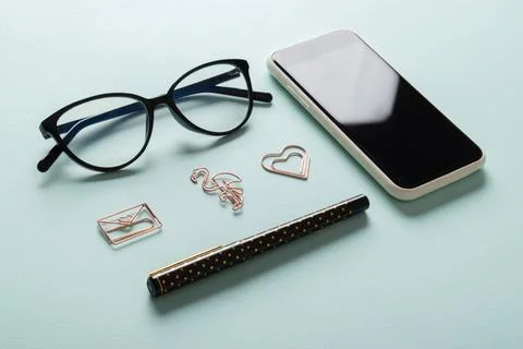 Smartphone, clean blank notepad, glasses, pen, paper clips, pencil on a light Foto stock