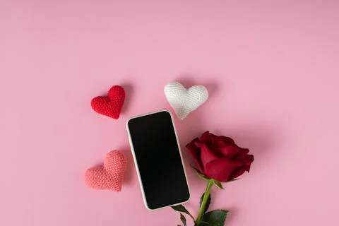 A smartphone with a clean screen with three knitted hearts and a red rose on  Stock Photos