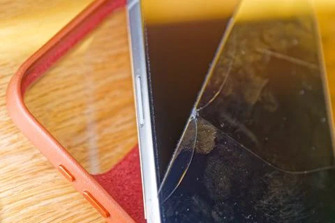 Smartphone with cracked screen and protective case on wooden surface Stock Photos