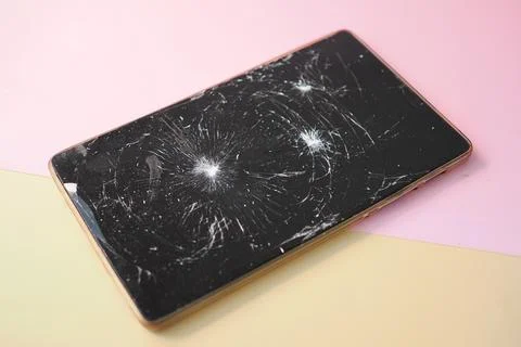 Smartphone with a cracked screen on a colored background Stock Photos