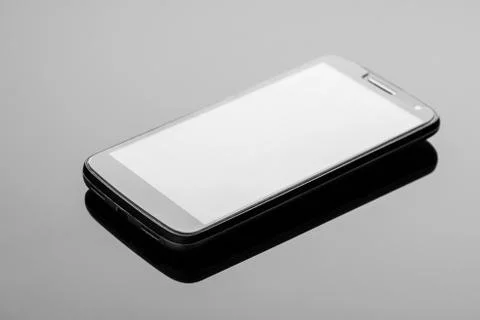 The smartphone on a dark glossy surface. Stock Photos