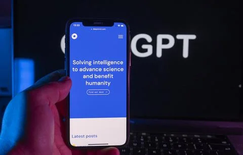 Smartphone with DeepMind website and in the background, the ChatGPT Stock Photos