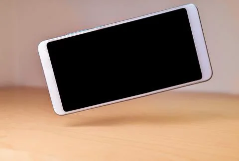 Smartphone device floating or levitating over a wooden table Stock Photos