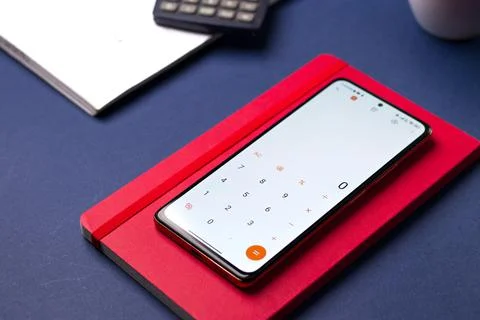 Smartphone displaying the calculator app with notes on a table Stock Photos