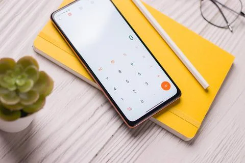 Smartphone displaying the calculator app with notes on a table Stock Photos