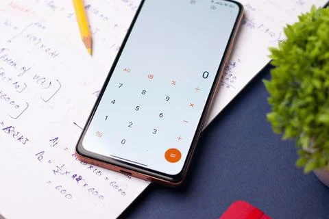 Smartphone displaying the calculator app with notes on a table Stock Photos
