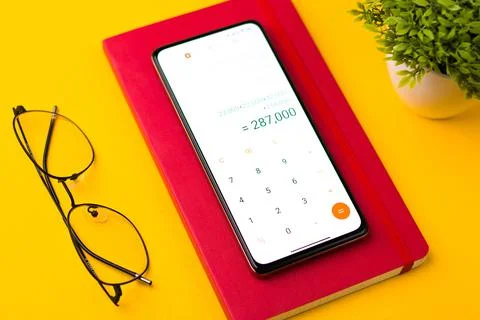 Smartphone displaying the calculator app with notes on a table Stock Photos
