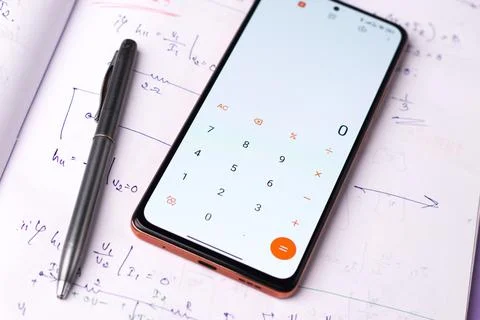 Smartphone displaying the calculator app with notes on a table Stock Photos
