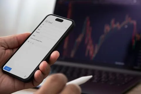 Smartphone displaying email compose screen with stylus near laptop showing .. Stock Photos
