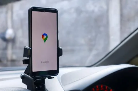 Smartphone displaying Google Maps navigation application mounted on car Stock Photos