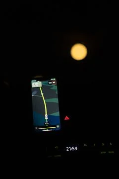 A smartphone displaying GPS navigation guides the way on a dark road illumi.. Stock Photos