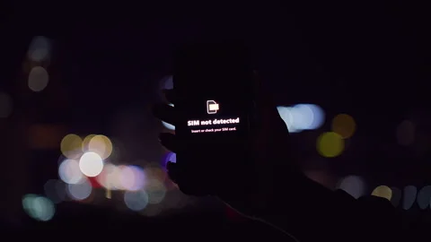 Smartphone Displaying SIM Not Detected Warning Held Against Night City Bokeh in Stock Footage 323466416