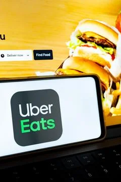 Smartphone displaying uber eats app logo on laptop keyboard Stock Photos