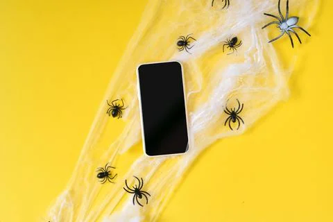 A smartphone with an empty black screen on a yellow background, a spider web. Фото