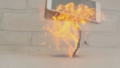 Smartphone explodes and burns while charging battery on desk at home Stock Footage 245141278